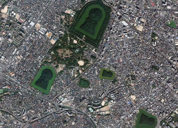 Вид с воздуха, на несколько гробниц в форме замочных скважин, которые усеивают пейзаж города Сакаи.